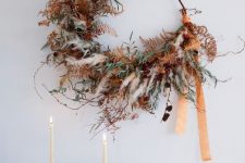 a unique and super textural Thanksgiving or fall wreath of pampas grass, greenery, dried leaves, pinecones and long ribbons is amazing