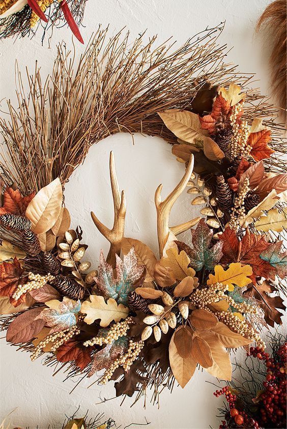a very bold and creative Thanksgiving or fall wreath of twigs, lots of bright faux leaves, berries, pinecones and antlers