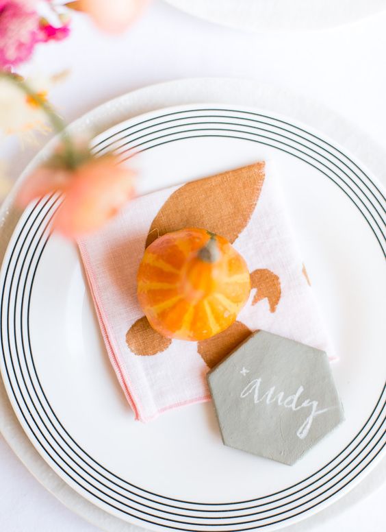 a very simple and lovely Thanksgiving place setting with a white and striped plate, a printed napkin, a gourd and a marble card