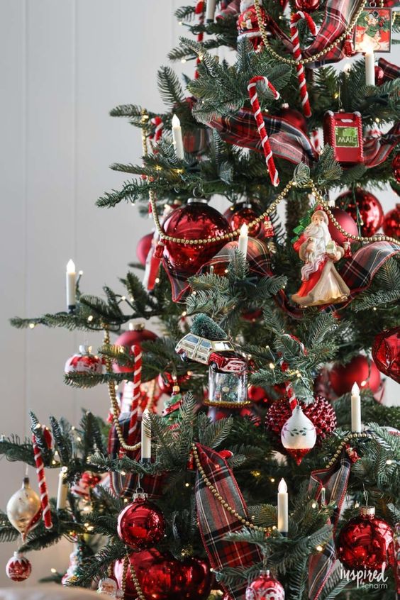 a vintage Christmas tree decorated with lots of vintage ornaments, beads, candle lights and candy cane ornaments