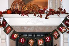 a vintage Thanksgiving mantel with bold leaves, pumpkins of porcelain and lights, a fabric garland and orange candles