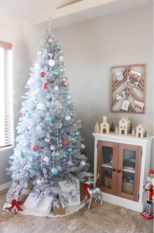 a vintage silver Christmas tree with blue, white and red ornaments and stacks of gift boxes and deer is a beautiful and refined idea