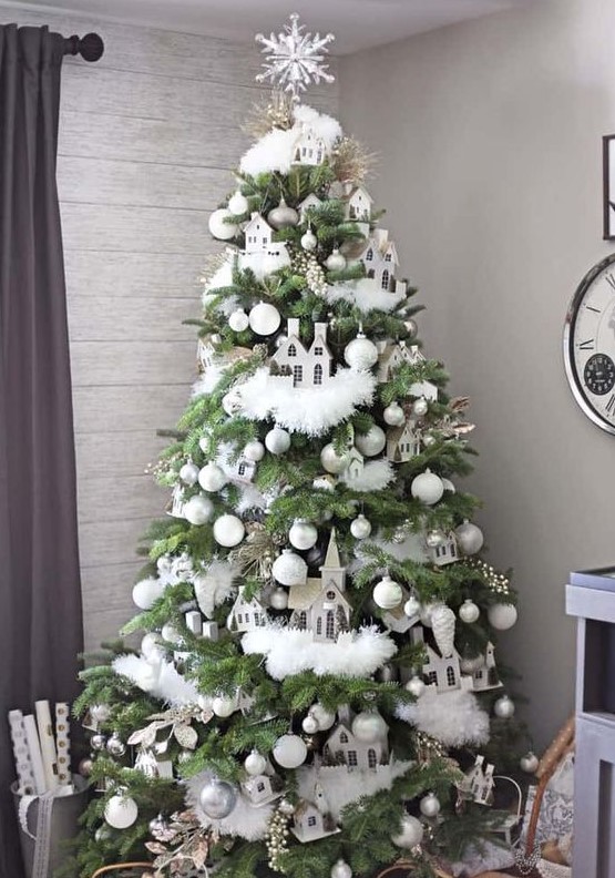 a whimsical neutral Christmas tree with white and silver ornaments, white faux fur garlands, berries, branches, houses and a snowflake tree topper