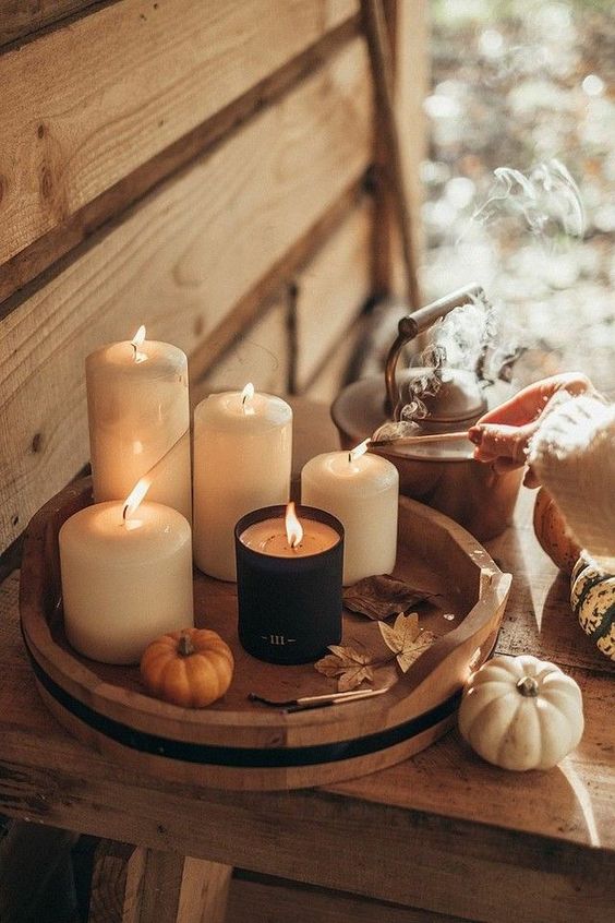 a wooden tray with pillar candles, leaves and a tiny pumpkin is a great Thanksgiving or fall decoration