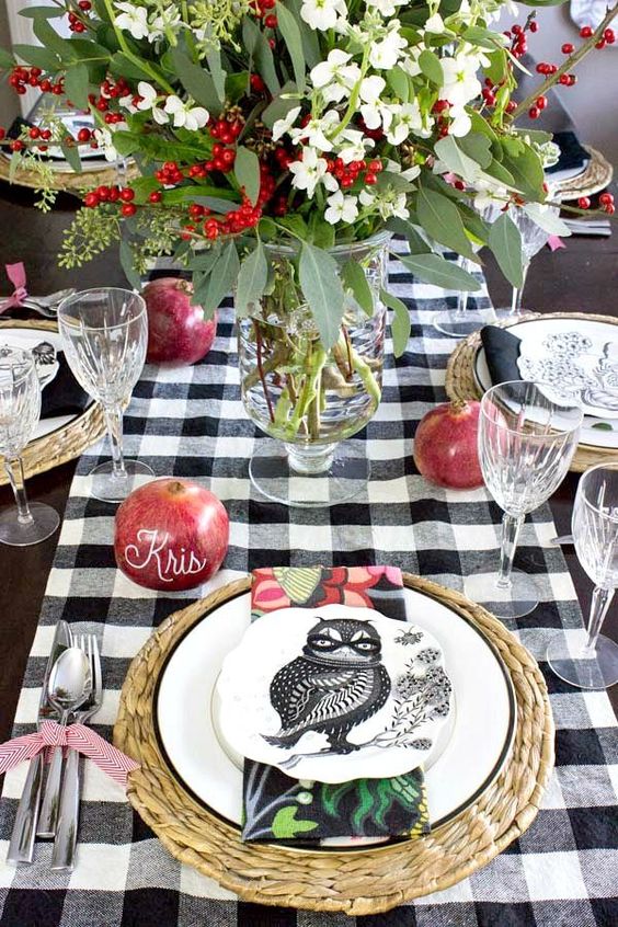 a woven placemat, a white plate with a black rim and a black and white owl printed plate plus a colorful napkin for a bold fall or Thanksgiving tablescape