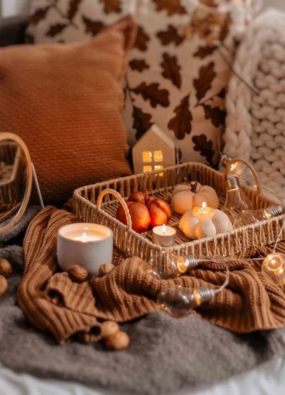 a woven tray with bulbs and lights, candles and faux pumpkins is a lovely fall or Thanksgiving decoration