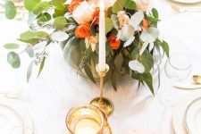 an elegant Thanksgiving centerpiece of a green pumpkin, orange and blush blooms and greenery plus tall and thin candles