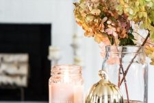 an elegant fall or Thanksgiving decoration of a wood slice, a candle in a jar, a gilded pumpkin and some dried hydrangeas in a jar