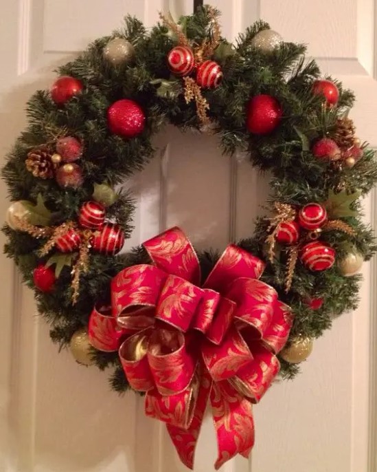 an evergreen Christmas tree of red and gold ornaments and ribbons, gilded pinecones and foliage