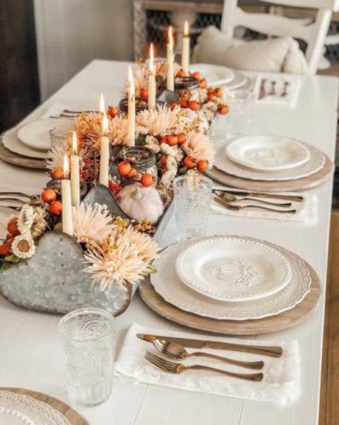 an eye-catchy Thanksgiving centerpiece of a metal tool box with blush and white blooms, berries and tall and thin candles