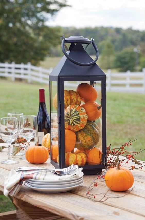 an oversized lantern filled with pumpkins and with berries is a cool rustic decoration you can easily make