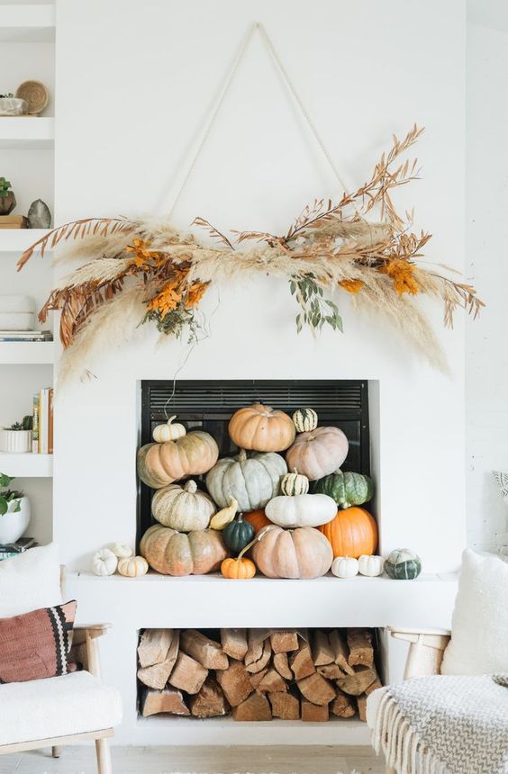 heirloom pumpkins stacked in the fireplace, a dried grass overhead installation and some firewood for fall and Thanksgiving