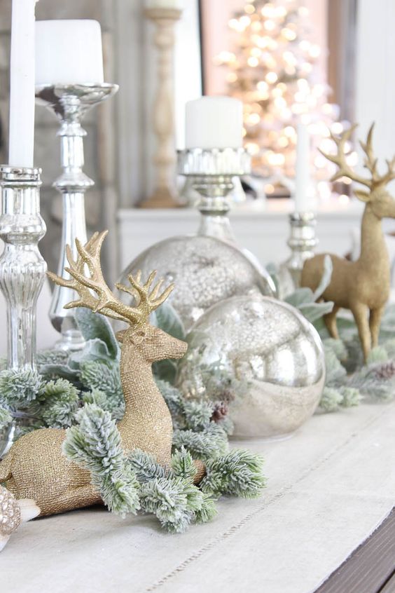 vintage Christmas decor with large silver ornaments, silver candleholders, snowy evergreens and gold deer