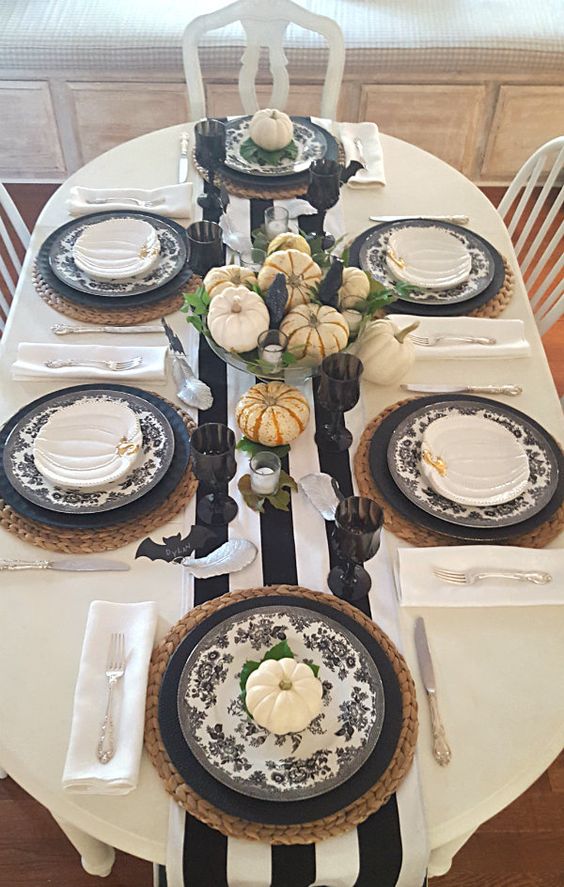 woven placemats, matte black plates and black and white floral ones, a single white pumpkin and small white pumpkin plates on top for a cool fall tablescape