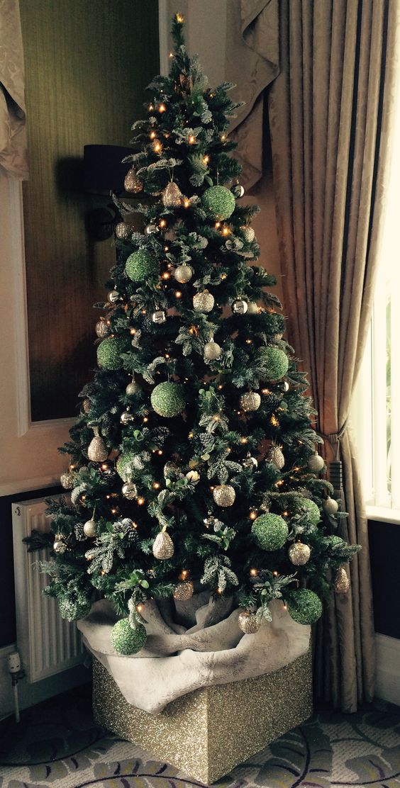 a Christmas tree decorated with green and gold glitter ornaments and lights is a super chic and glam idea