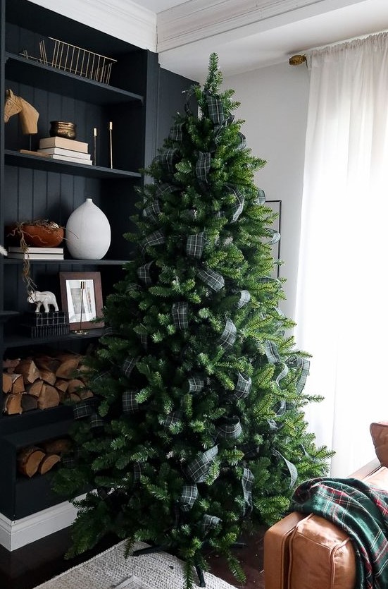 a Christmas tree decorated with only dark green plaid ribbon and nothing else is a very fresh and bold solution with a rustic feel