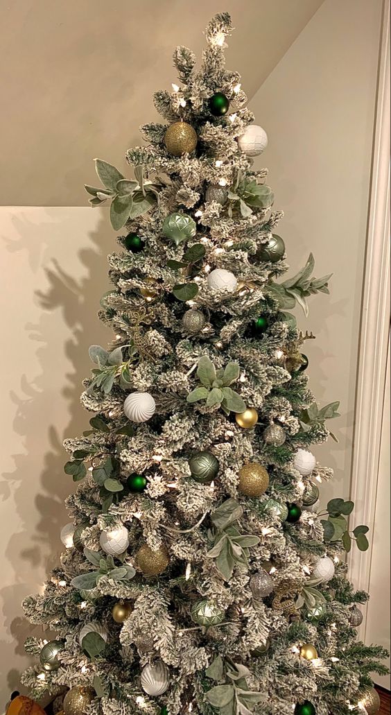 a Christmas tree with white, green and gold ornaments, lights and foliage looks gorgeous and chic