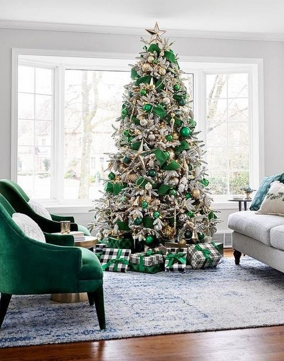 a beautiful flocked Christmas tree decorated with emerald and silver ornaments, emerald ribbons, lights and pinecone ornaments in gold