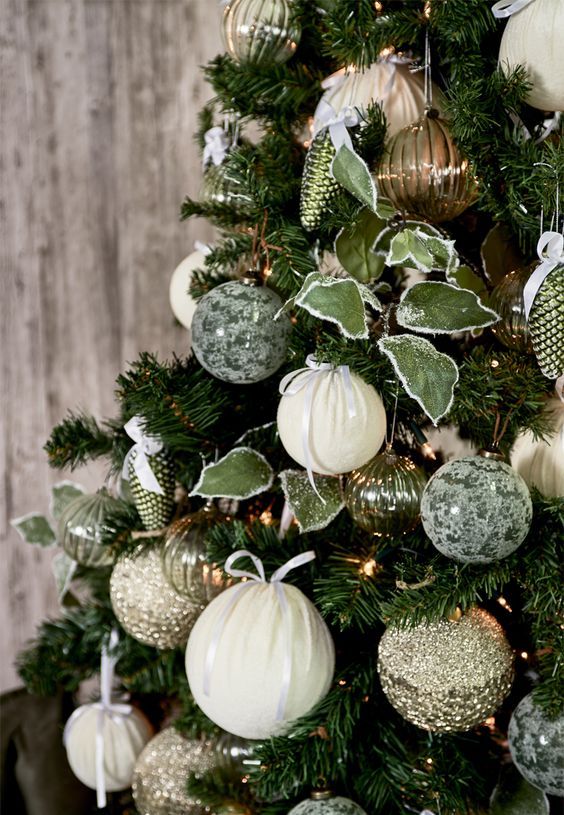 a beautiful green Christmas tree with white, gold and green patterned ornaments, leaves, lights and ribbons is a chic decoration