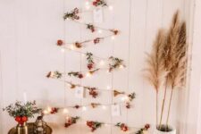 a boho wall-mounted Christmas tree of lights, berries and Christmas cards plus pampas grass and blooms around
