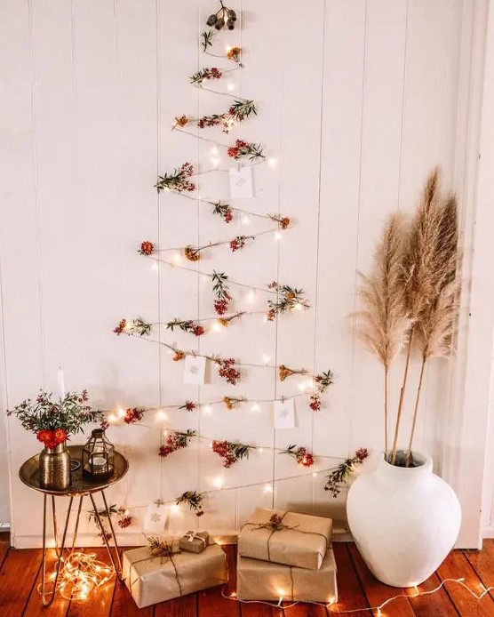 a boho wall-mounted Christmas tree of lights, berries and Christmas cards plus pampas grass and blooms around