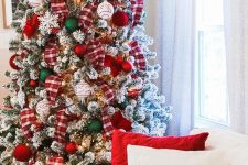 a bold flocked Christmas tree with plaid ribbons, red, white and green ornaments, berries and lights is a bold and chic idea