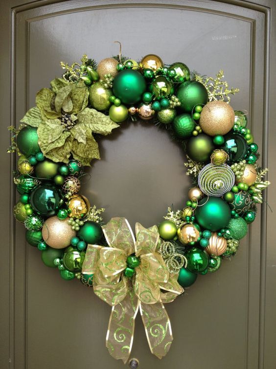a bold green and gold Christmas ornament wreath with fabric blooms, snowflakes and a large bow is a stylish idea to rock