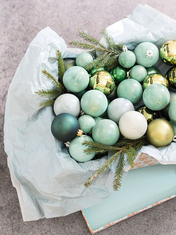 a bowl with pastel green paper, pastel green and dark green ornaments, evergreens is a lovely decoration or a centerpiece