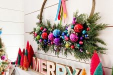 a bright Christmas mantel with wooden letters, colorful botle cleaner trees, a bold wreath with shiny and bright ornaments for Christmas