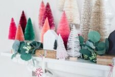 a chic Christmas mantel decorated with colorful bottle brush trees, fau greenery, a peppermint garland and mini houses
