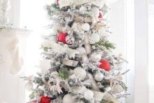 a chic flocked Christmas tree with white and burlap ribbons, white and metallic ornaments and oversized red ones