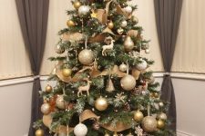 a classic Christmas tree with deer figurines, white, gold and glitter ornaments, burlap ribbons, pinecones, pears and lights all over
