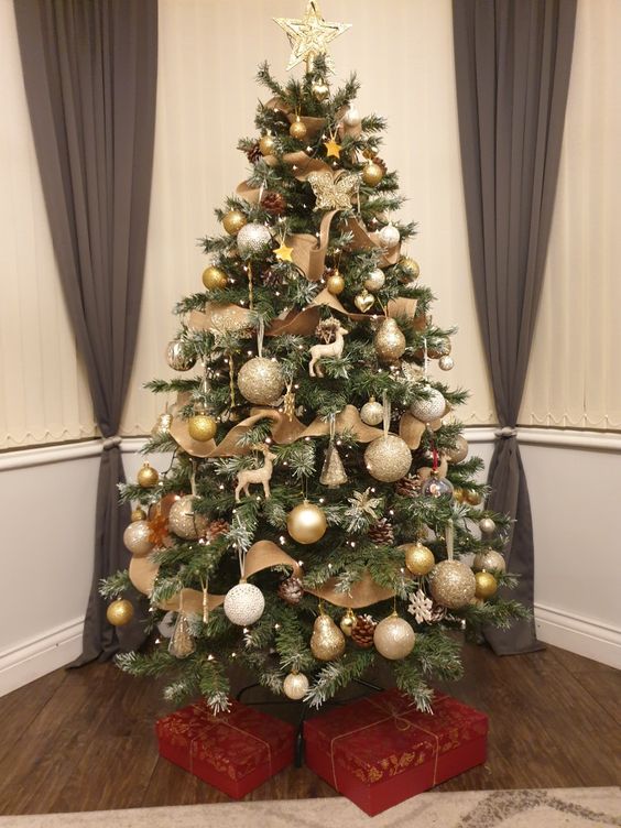 a classic Christmas tree with deer figurines, white, gold and glitter ornaments, burlap ribbons, pinecones, pears and lights all over