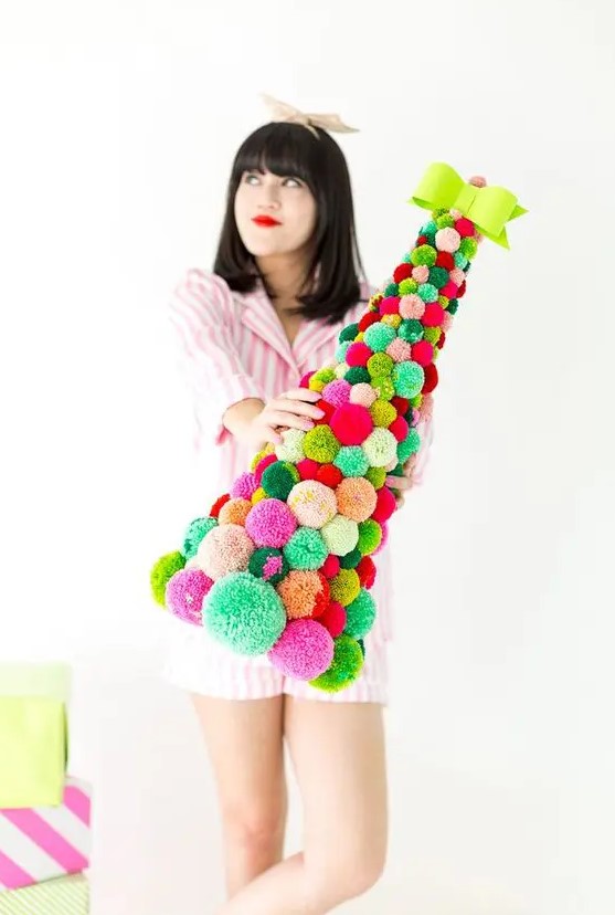 a colorful pompom cone-shaped Christmas tree topped with a bold bow is an amazing idea for bright holiday decor