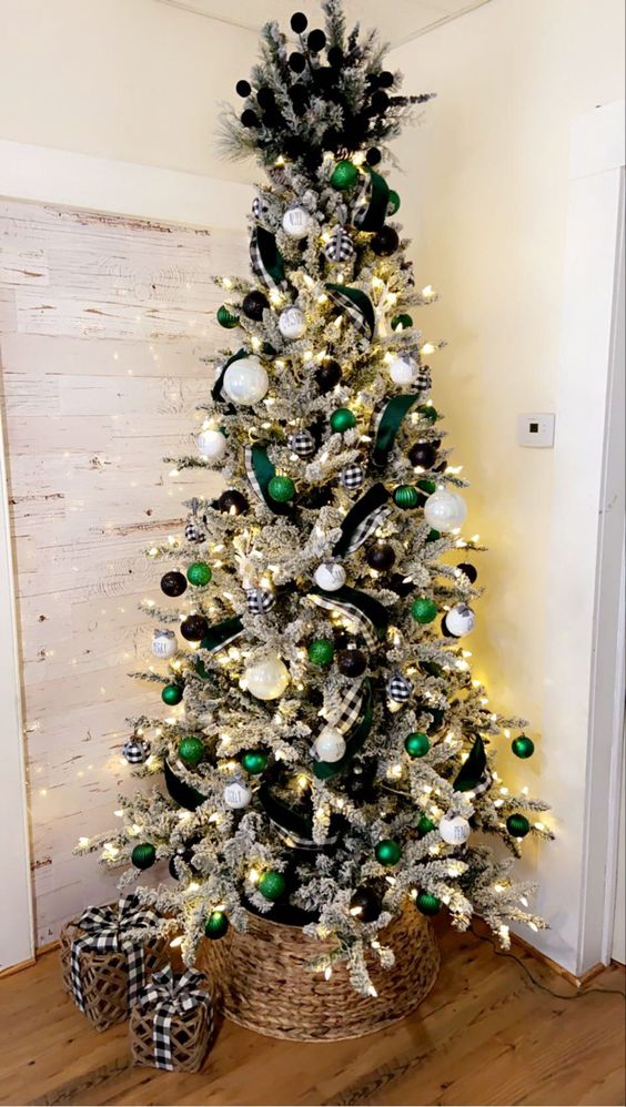 a cool farmhouse flocked Christmas tree decorated with black, emerald and white ornaments, lights, branches and buffalo check ribbons
