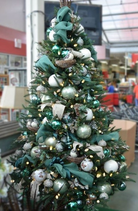 a dreamy Christmas tree with white and light green ornaments, dark green ribbons, acorns and lights plus faux birds in nests is wow