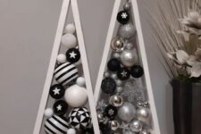 a duo of white tabletop frame Christmas trees with silver, black and white ornaments inside is a cool idea for a modern space