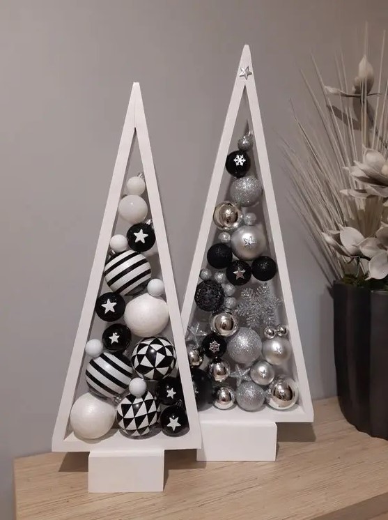 a duo of white tabletop frame Christmas trees with silver, black and white ornaments inside is a cool idea for a modern space