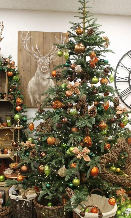 a fabulous woodland glam Christmas tree with copper, orange, light green ornaents, pinecones, vines and vine decorations is amazing