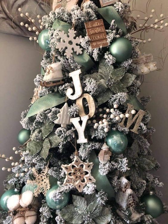 a farmhouse christmas tree decorated with wooden letters, beads, twigs, branches, snowflakes and green ornaments and leaves