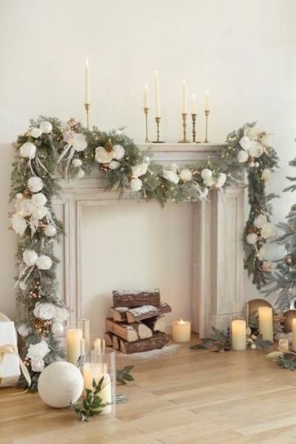 a faux mantel with an evergreen, pinecone, pompom and light garland, tall and thin candles, pillar ones on the floor