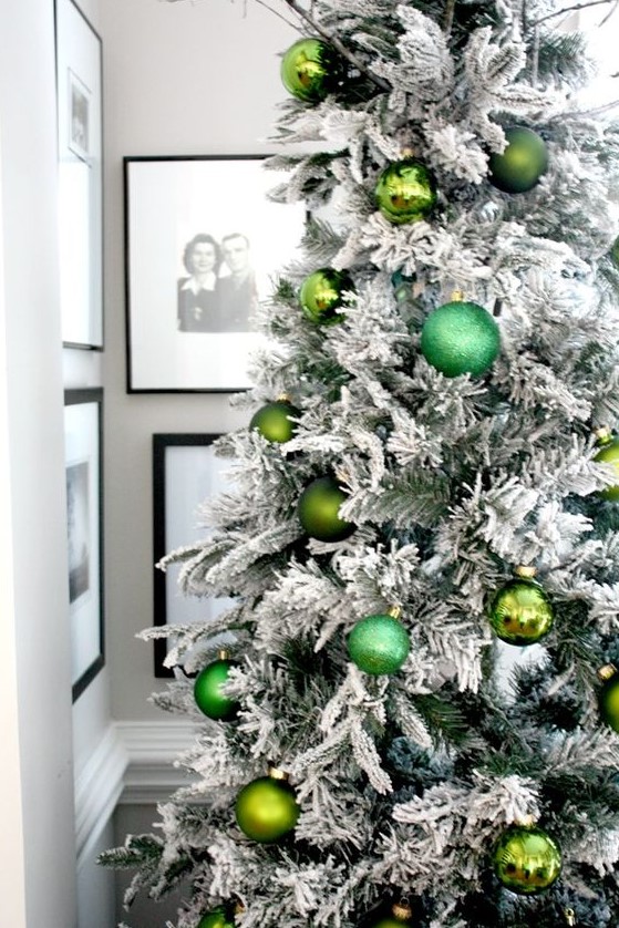 a flocked Christmas tree decorated with green ornaments of various shades looks glam, chic and bold and feels pretty natural at the same time