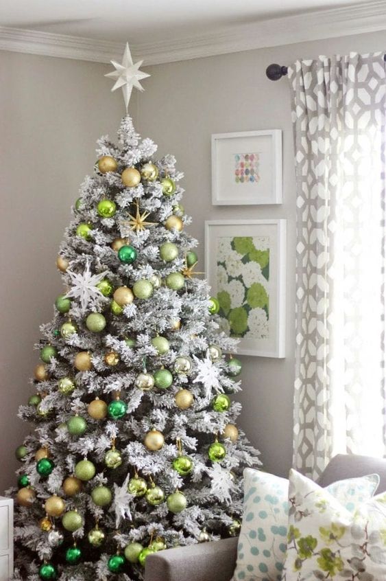 a flocked Christmas tree with neon green, emerald and gold ornaments, snowflakes and a star topper is a cool idea