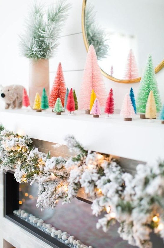 a fun modern Christmas mantel with colorful bottle brush trees, a flocked evergreen garland with lights