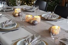 a glam Christmas table with a geometric table runner, gold chargers, grey napkins and silver and gold ornaments and candles