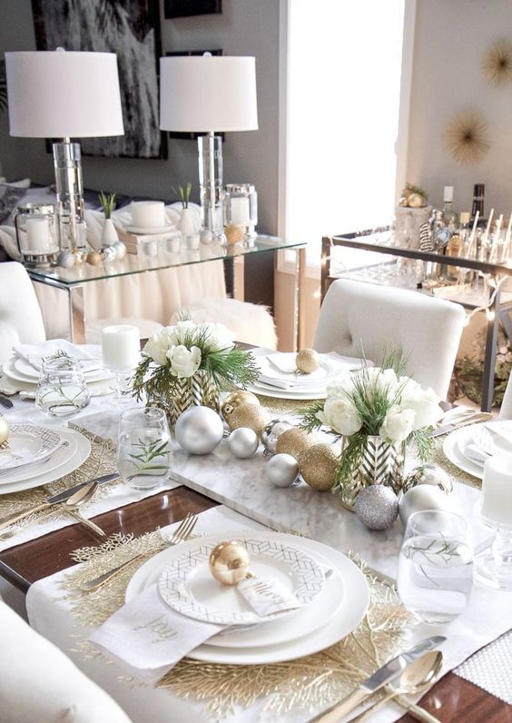 a glam and elegant Christmas tablescape with gold glitter and silver ornaments, gold placemats, white blooms and greenery and elegant white plates