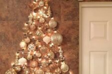 a glam wall-mounted Christmas tree done with lights and white and silver ornaments of various shapes over the mantel