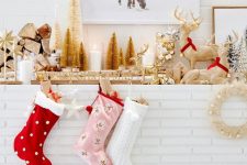 a glam woodland Christmas mantel with gold bottle cleaner trees, mismatching stockings, some deer figurines and bells in a jar