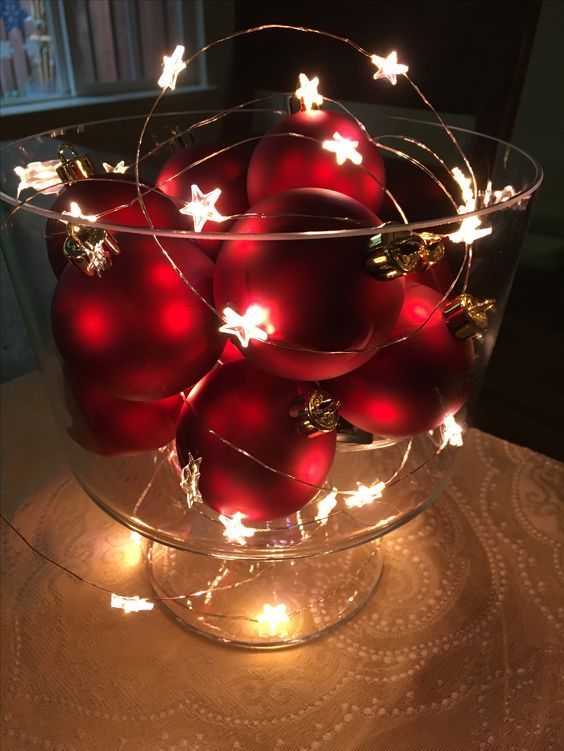 a glass bowl with red Christmas ornaments and a star light garland is a cool winter decoration