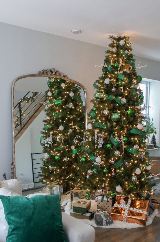 a gorgeous Christmas tree styled with emerald ornaments and ribbons, white and silver ornaments, lights and large snowflakes looks wow